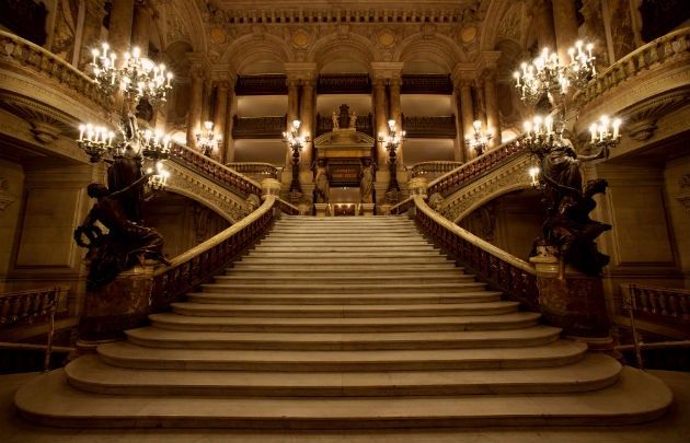 an ornate staircase with chandeliers and lights in a large palace like building that is lit up at night