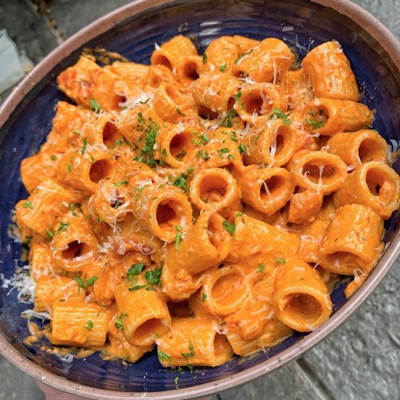 a blue bowl filled with pasta and cheese