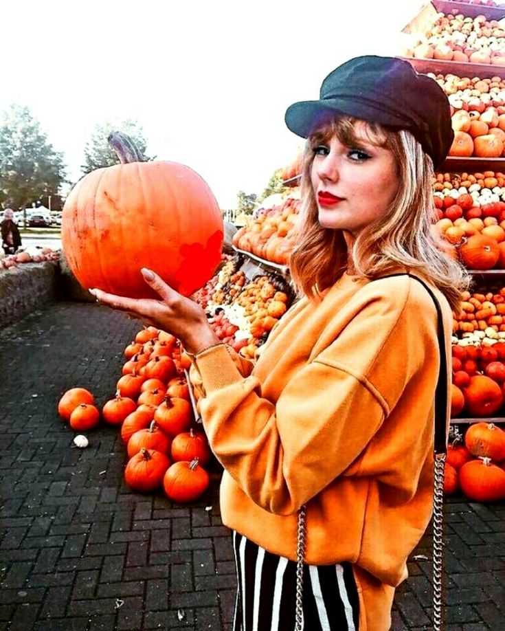 a woman is holding a pumpkin in her hand