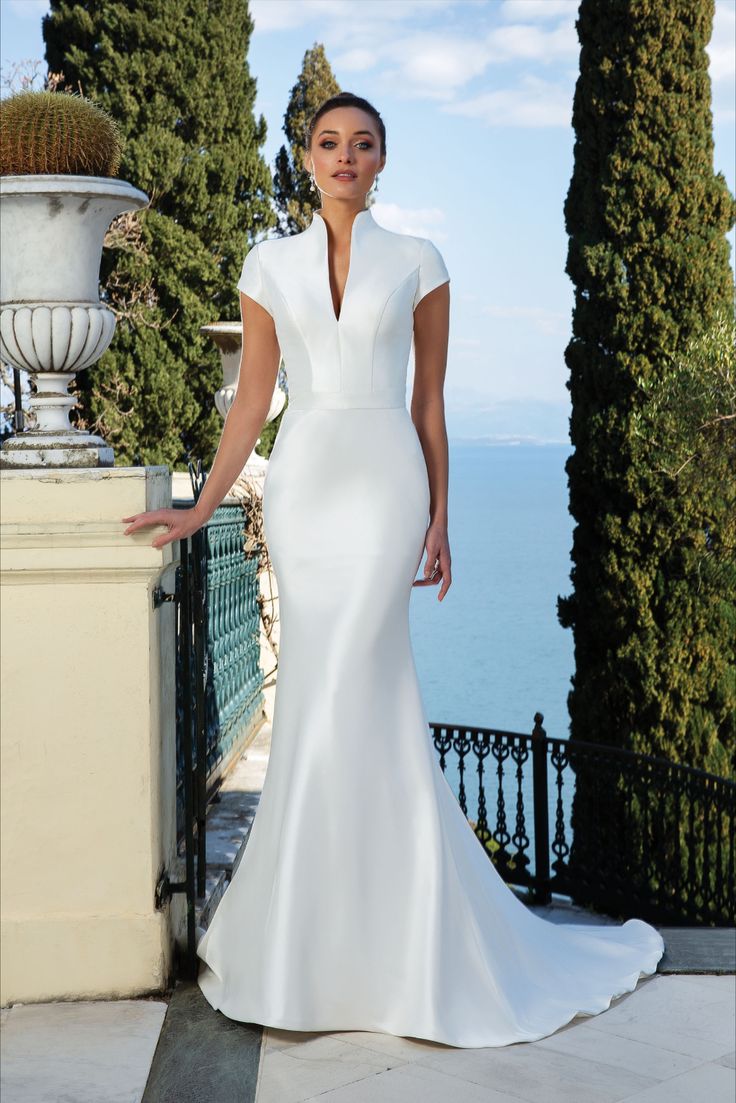 a woman in a white dress standing next to some trees