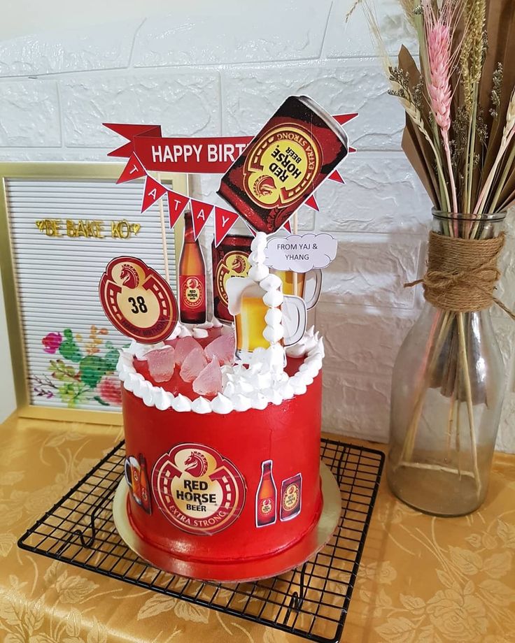 a red birthday cake with beer and decorations on the top is sitting on a table