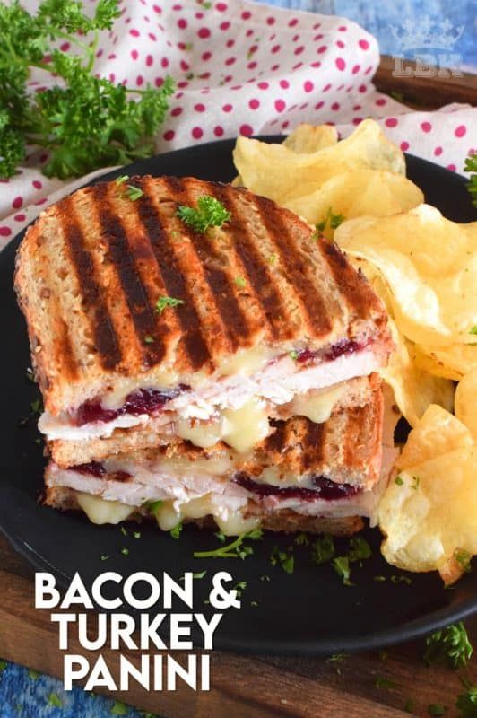 a grilled sandwich and potato chips on a black plate