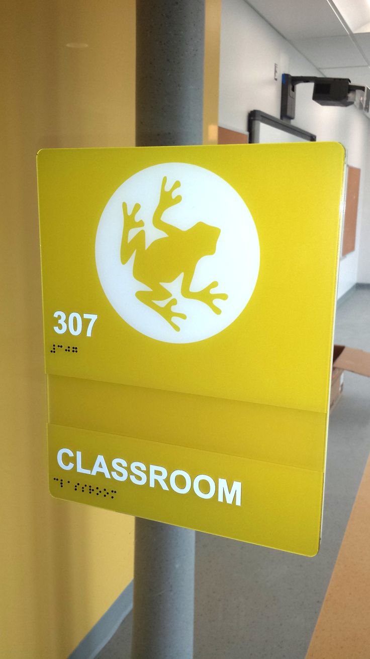 a yellow sign that says classroom with a frog on it's back and white lettering