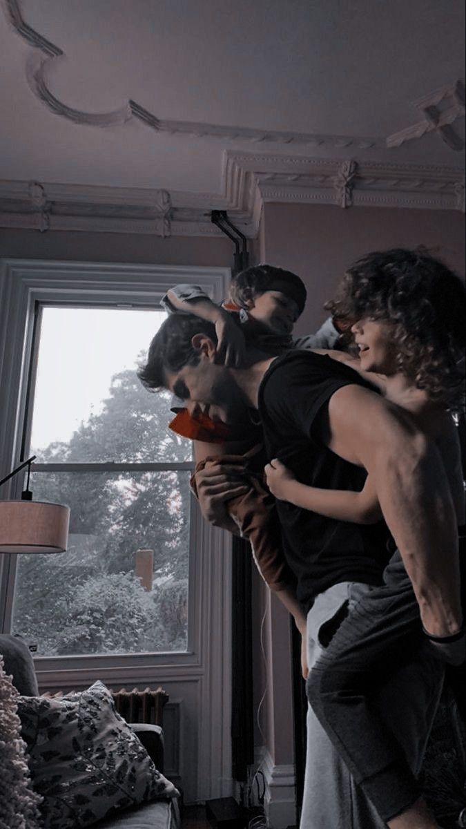 a group of young men standing next to each other in front of a living room window