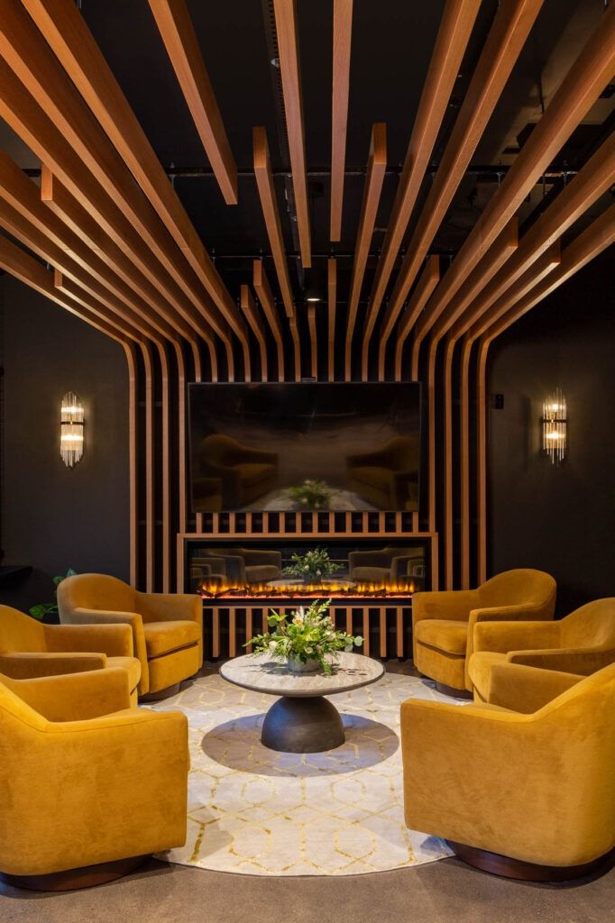 a living room filled with yellow chairs and a round table in front of a fireplace