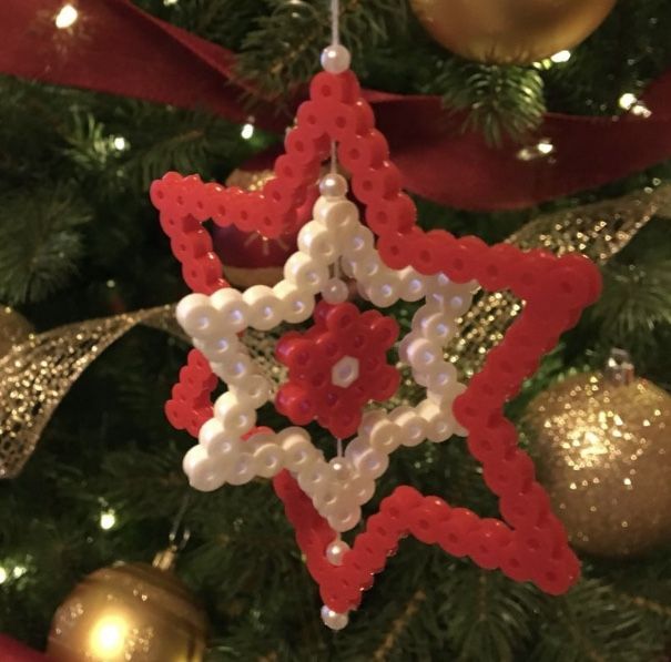 a red and white star ornament hanging from a christmas tree