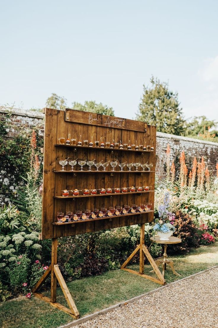 a wooden display case filled with lots of jars on top of a grass covered field