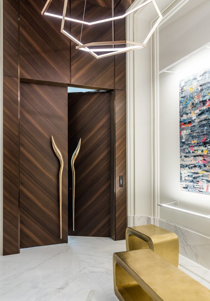 the entrance to an office building is decorated with wood and gold accents, along with a marble bench