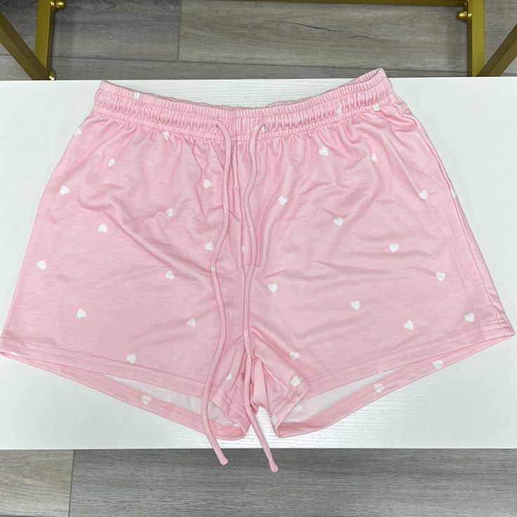 Pink Short With White Hearts And Pockets Trendy Bottoms With Heart Print For Summer, White Heart Print Bottoms For Summer, Trendy Summer Bottoms With Heart Print, Trendy Heart Print Bottoms For Summer, Trendy Heart Print Summer Bottoms, Casual White Bottoms With Heart Print, Pink Heart Print Bottoms For Summer, Cute Pink Cotton Pajama Shorts, Casual Pink Athletic Shorts With Built-in Shorts