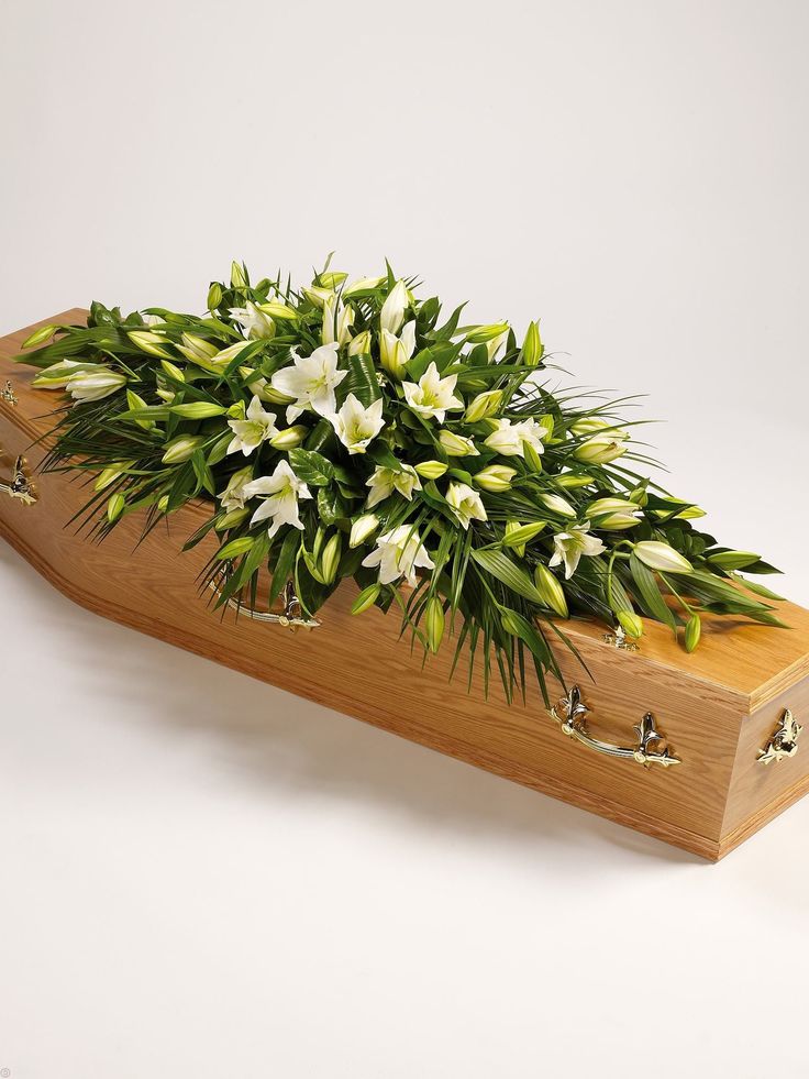 a wooden box filled with white flowers on top of a table