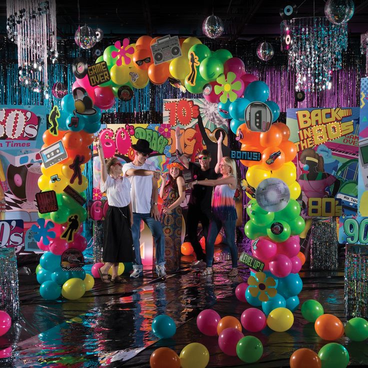 a group of people standing on top of a stage surrounded by balloons and streamers