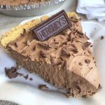 a piece of chocolate pie on a white plate with a name tag that reads hershey's