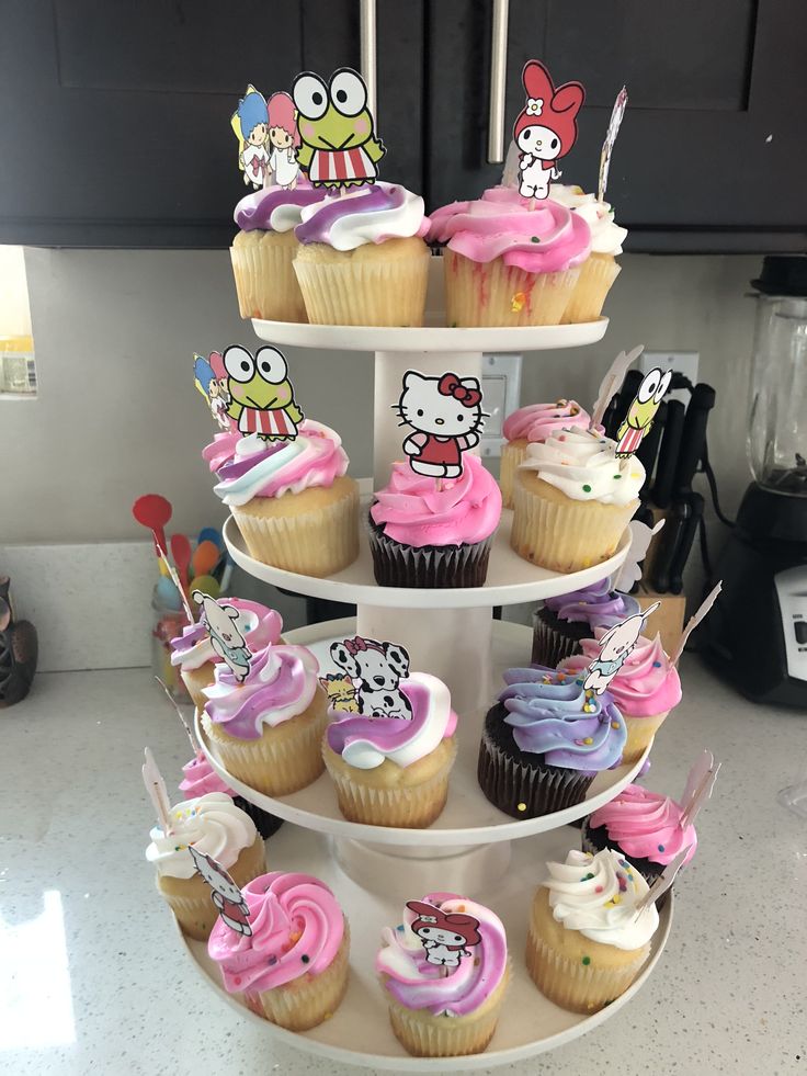 a three tiered cupcake display with hello kitty decorations on it's sides