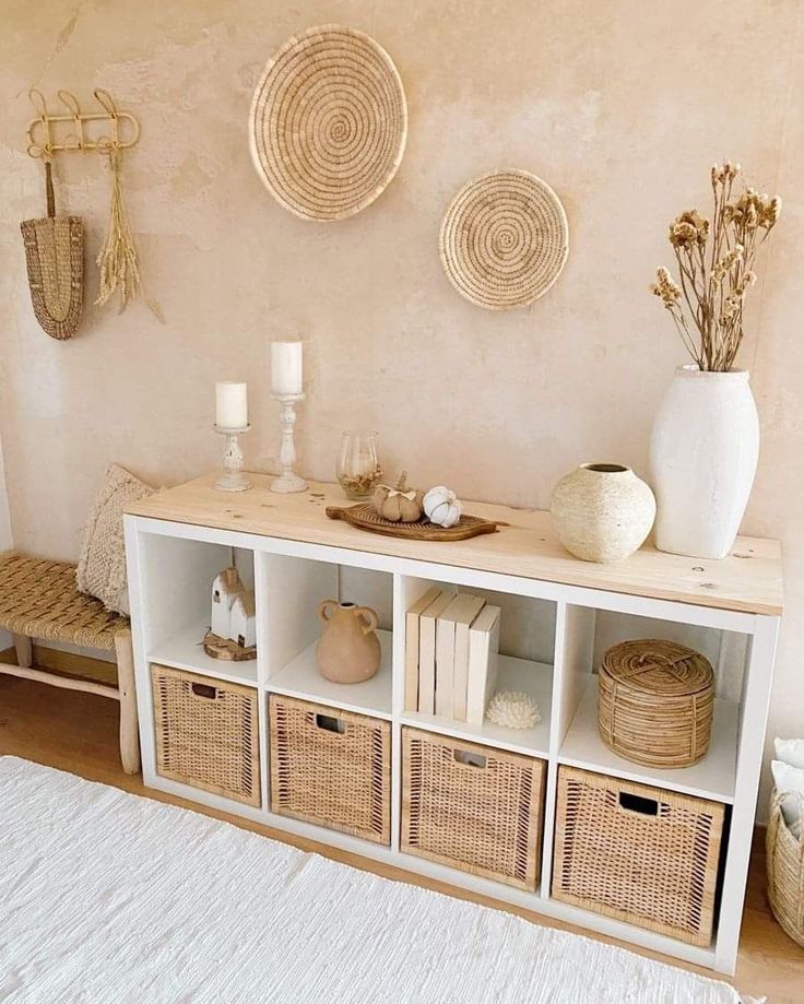 a white shelf with baskets and candles on it in front of a wall mounted wicker basket