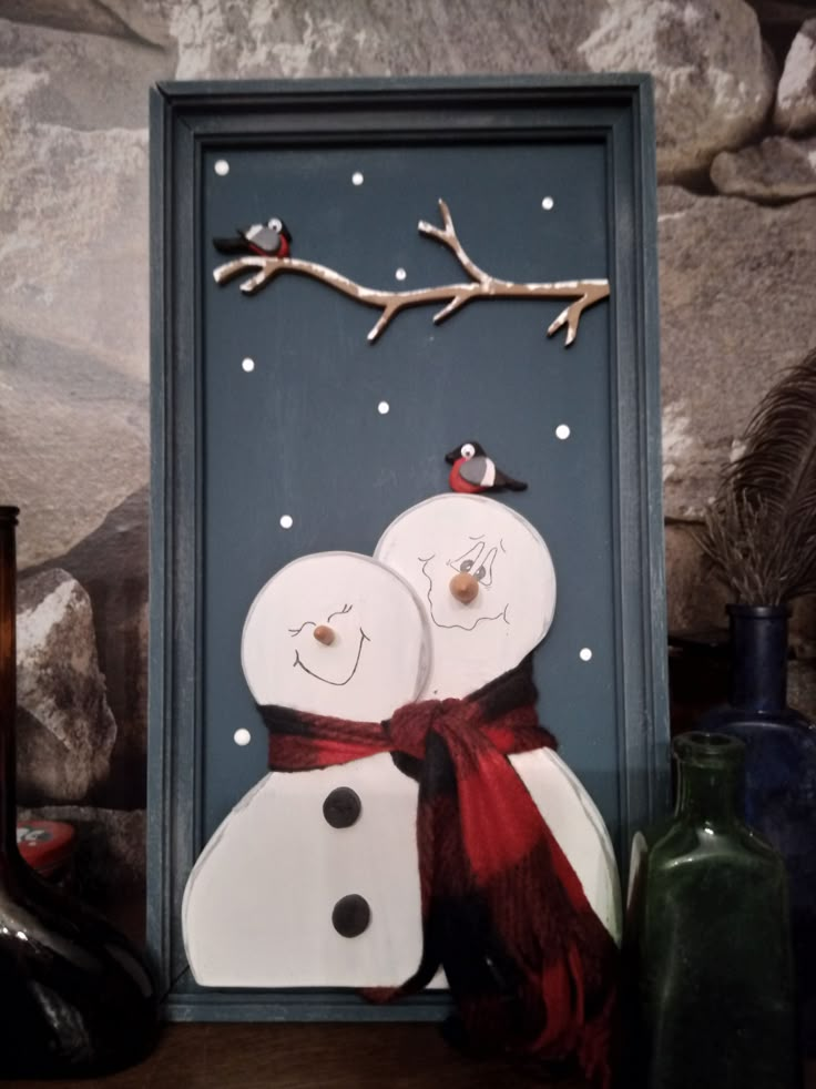 two snowmen are standing next to each other in front of some bottles and rocks