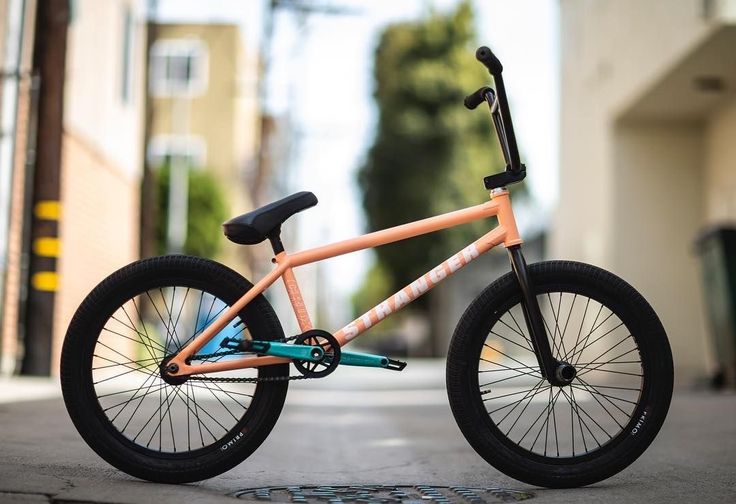 an orange and blue bike parked on the side of a road next to a building