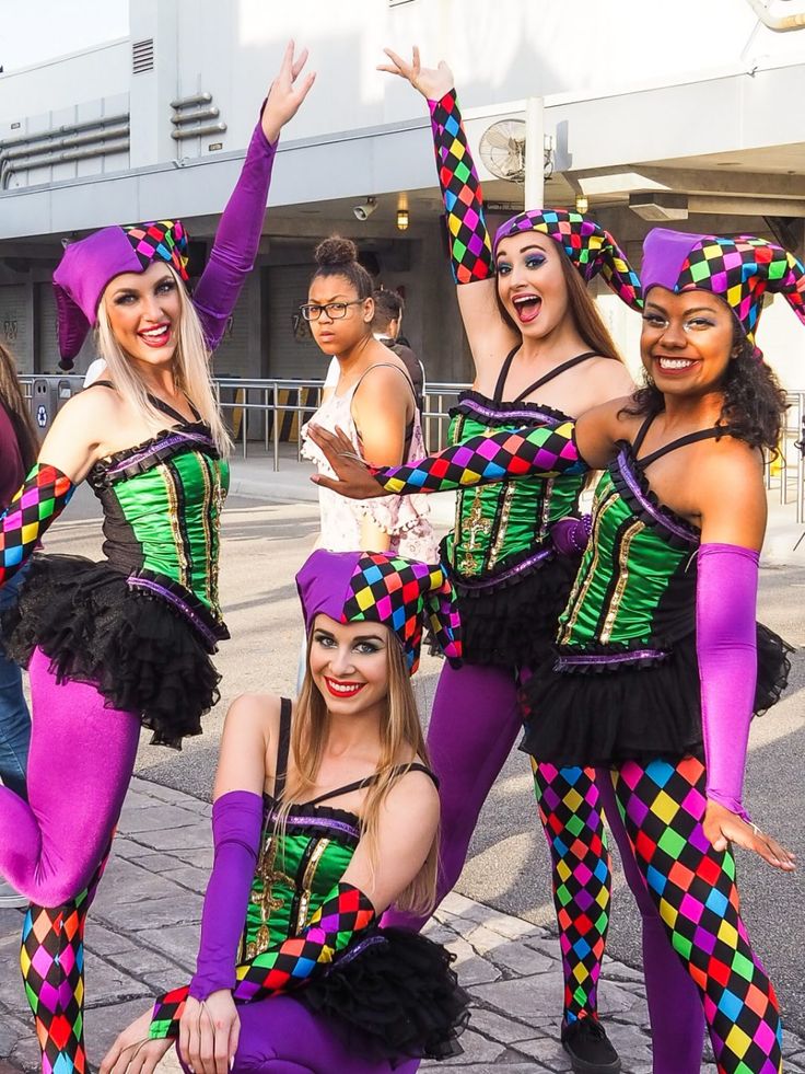 a group of women dressed in colorful costumes posing for a photo with their hands up