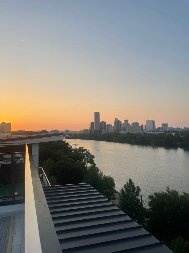 the sun is setting over a body of water with stairs leading up to it and buildings in the background