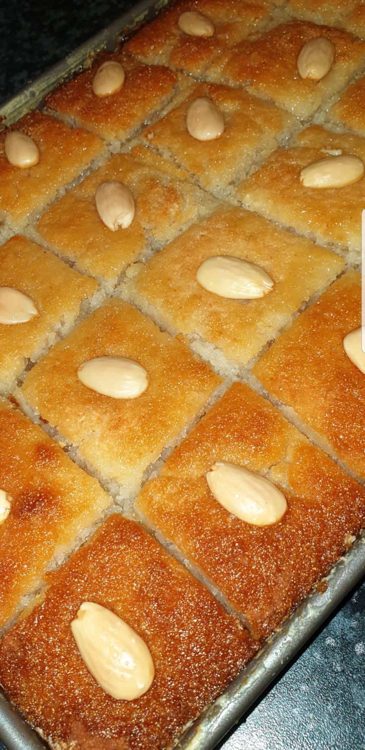 a pan filled with cake covered in almonds on top of a counter next to a knife