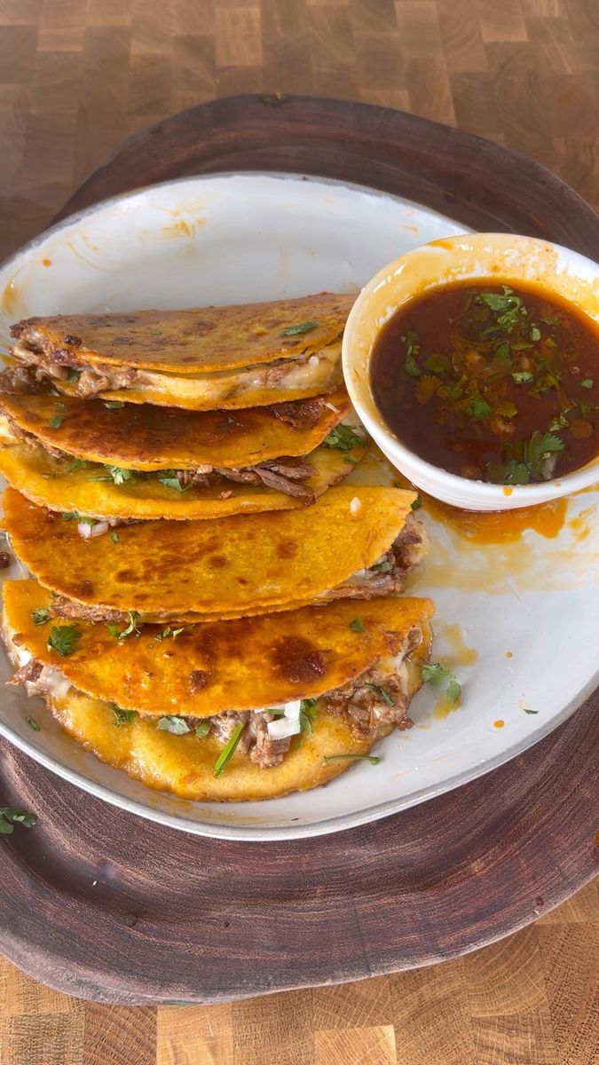 a plate topped with quesadillas next to a bowl of salsa