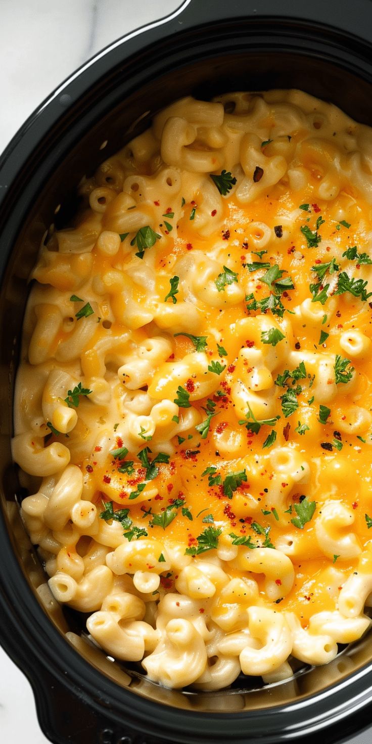 macaroni and cheese in a slow cooker with parsley sprinkled on top