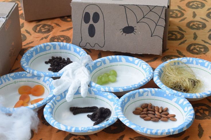 four paper plates with halloween food in them on a table next to a cardboard box