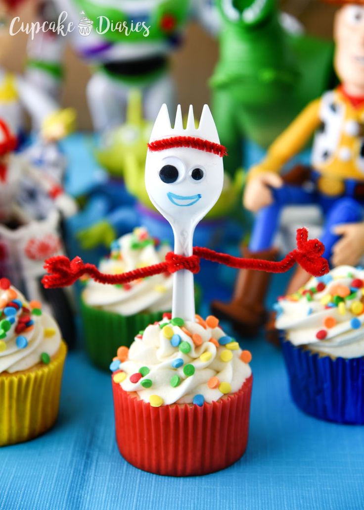 cupcakes with frosting and sprinkles are on a blue tablecloth