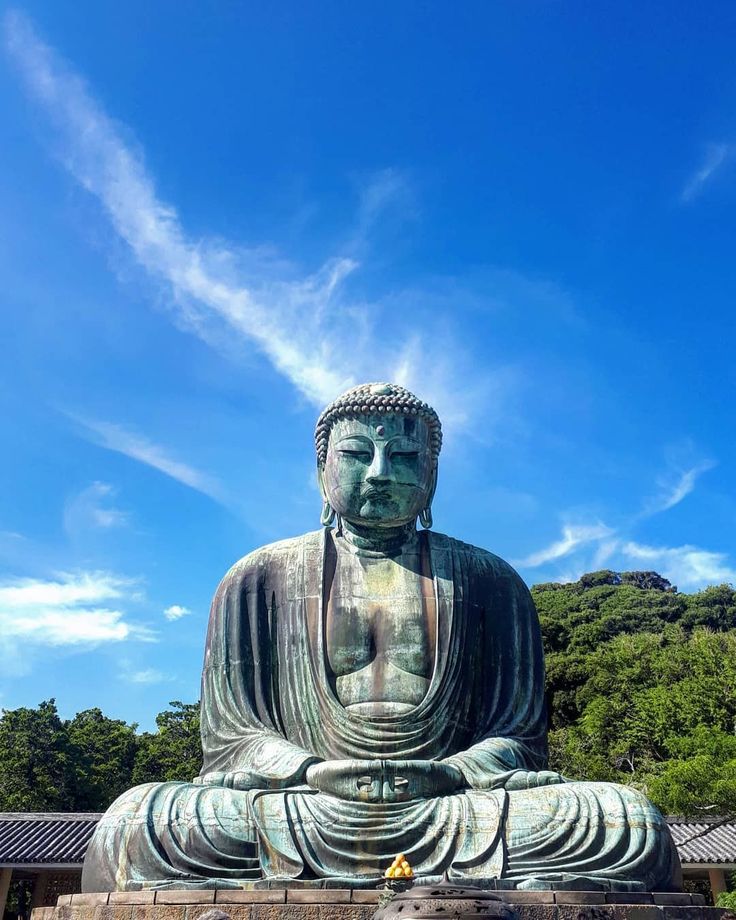 a large buddha statue sitting on top of a lush green field