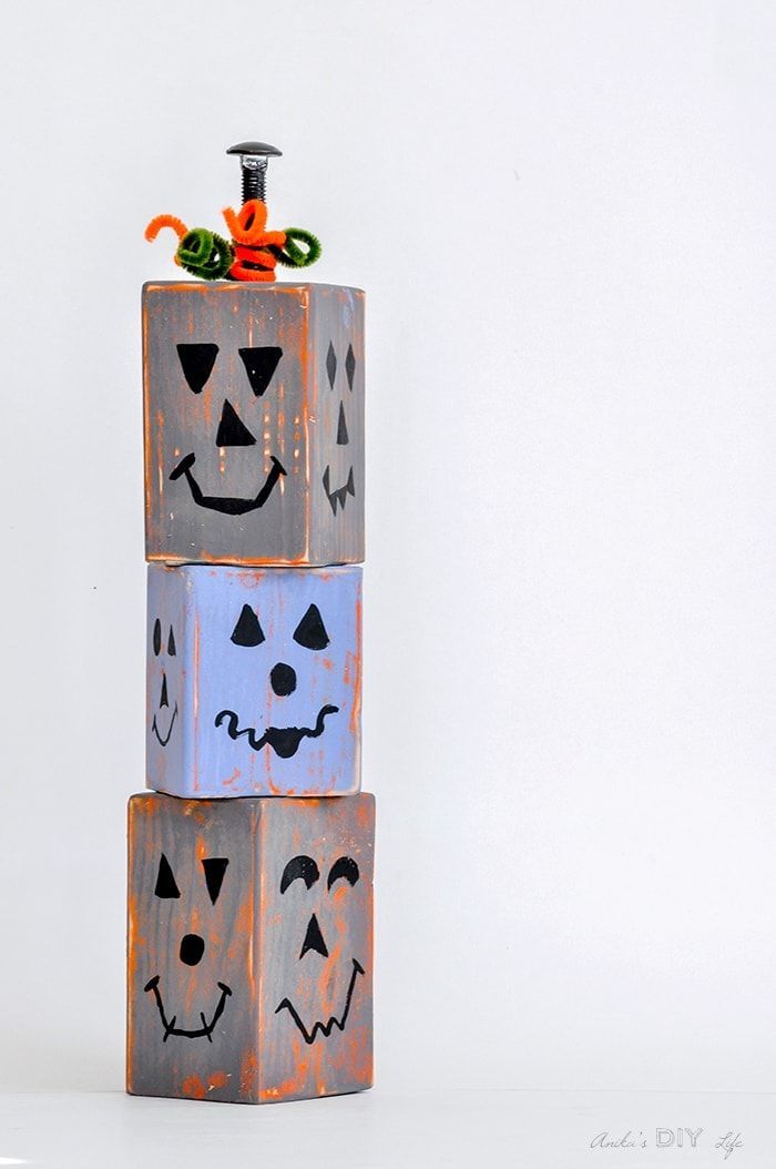 three blocks with faces painted on them are stacked up in the shape of pumpkins