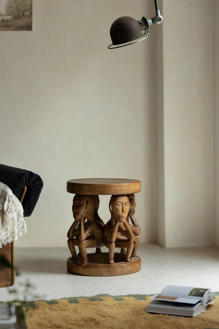 a wooden table sitting in the middle of a room next to a chair and lamp