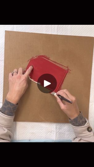 a person is drawing on a piece of cardboard