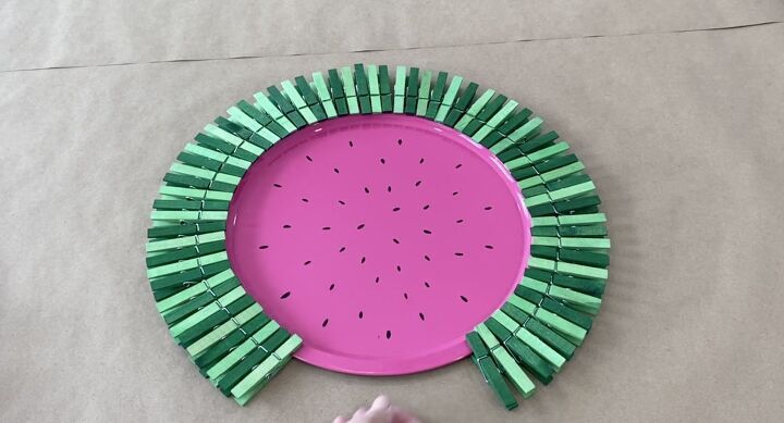 a pink paper plate with green sticks sticking out of it and a hand reaching for one