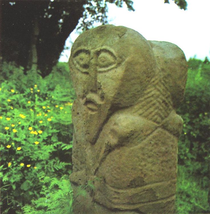 a stone statue sitting on top of a lush green field