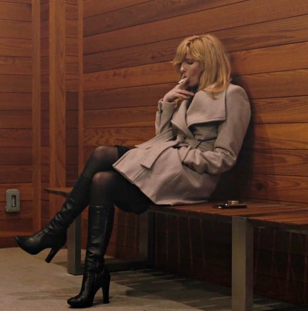 a woman sitting on top of a wooden bench next to a wall with wood paneling