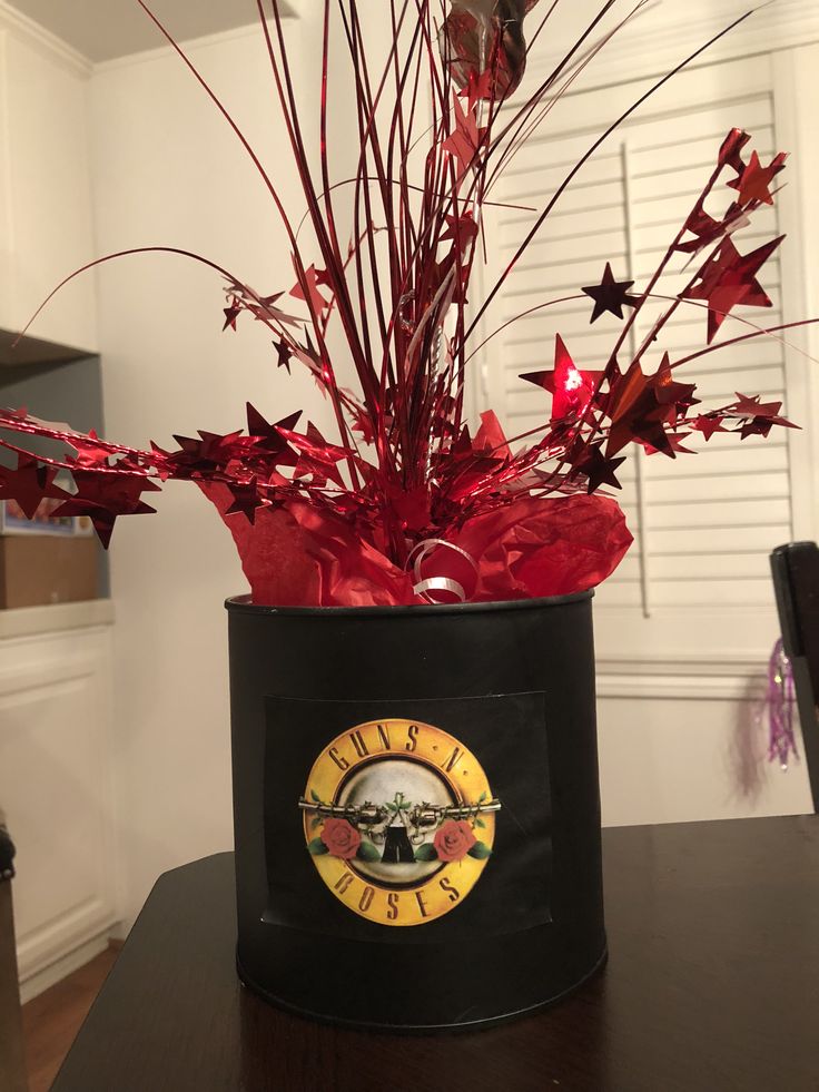 a black hat with red flowers in it on top of a wooden table next to a window