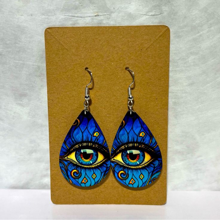 a pair of blue earrings with an eye painted on the front and back of it