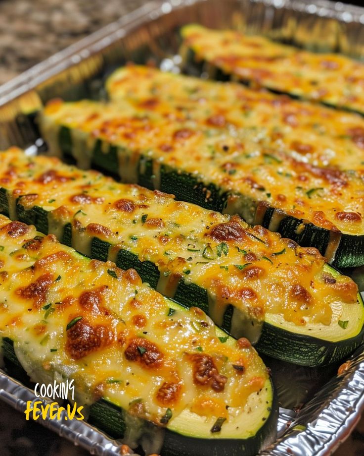 several cooked zucchini slices in a metal pan on a counter top with cheese and seasoning