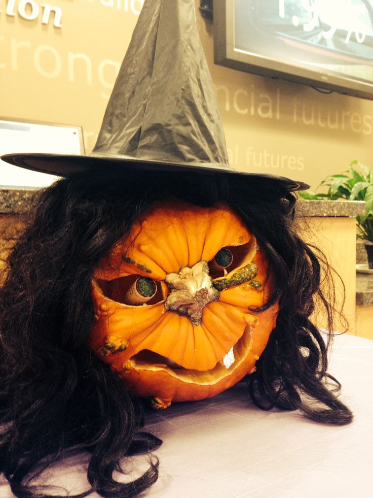 a pumpkin with a witch's hat and long black hair on top of a table