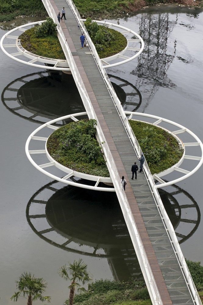 two people walking across a bridge over water