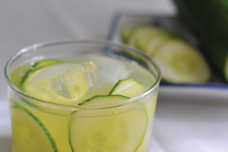 a glass filled with cucumber slices on top of a table