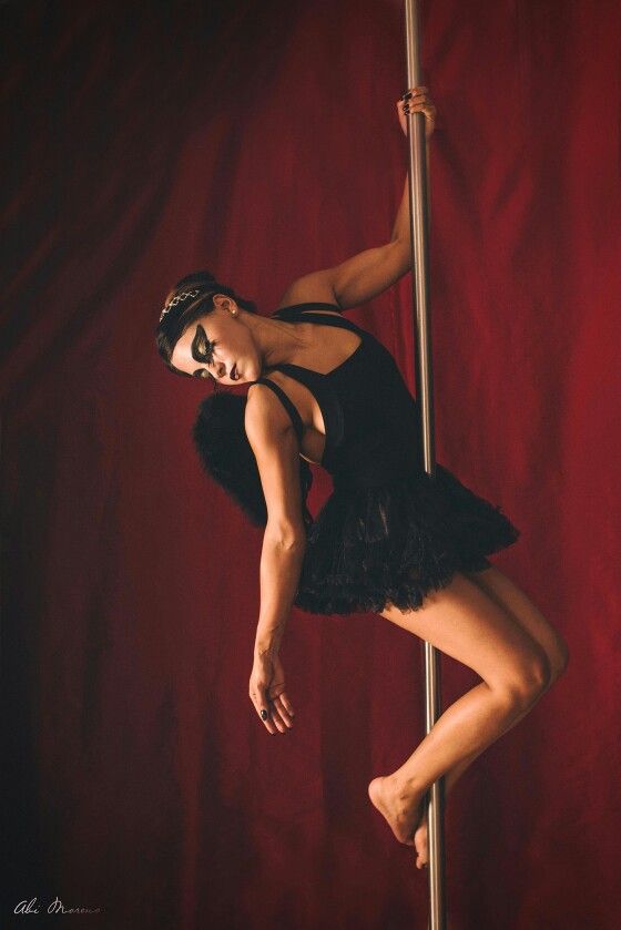 a woman in a black leotard is leaning on a pole