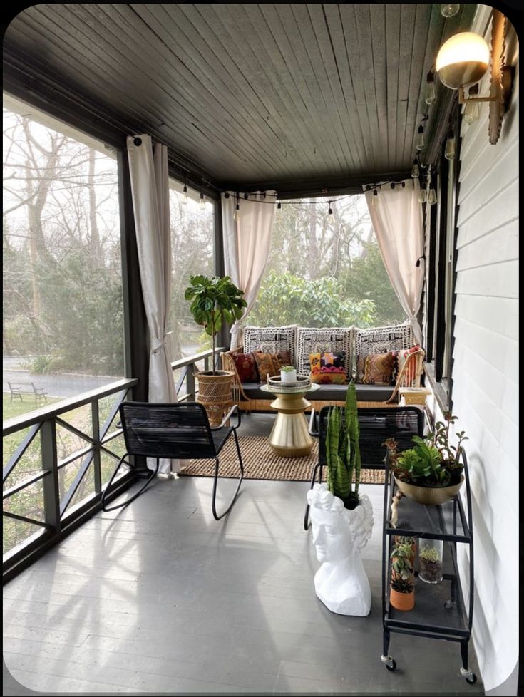 a covered porch with chairs and plants on it