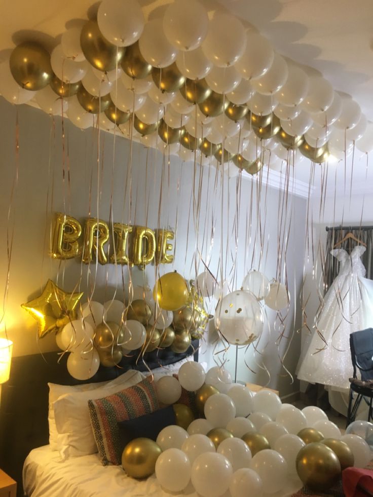 balloons and streamers are hanging from the ceiling above a bed in a bridal party