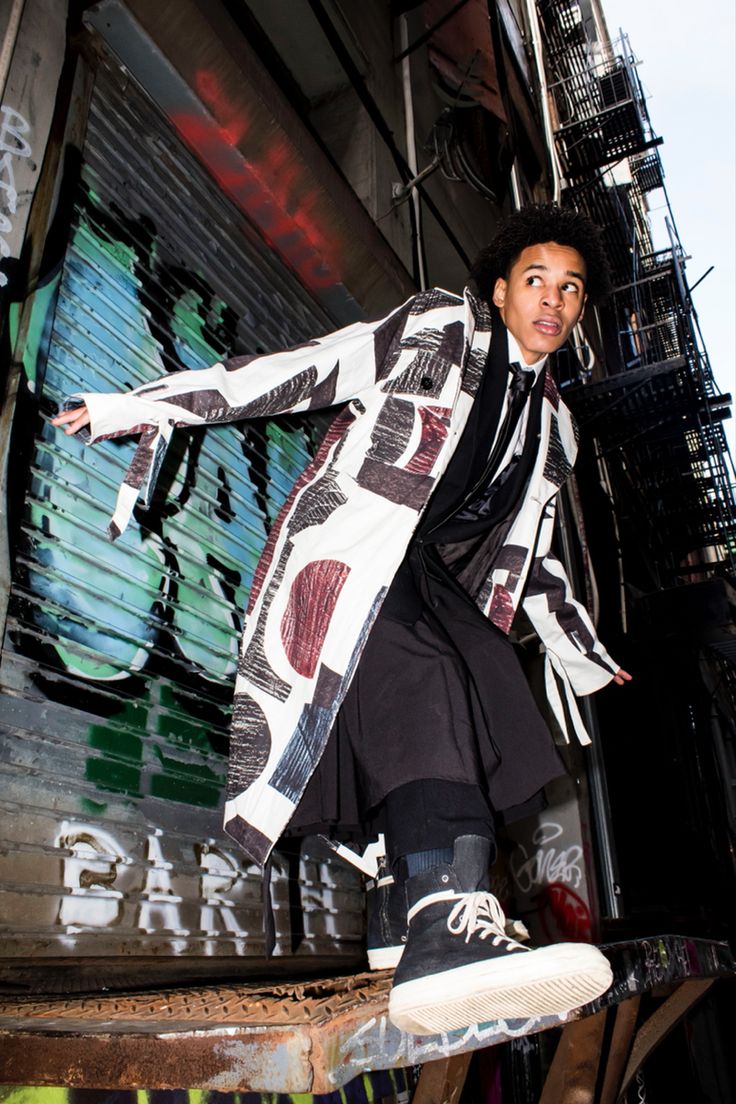 a man standing on top of a skateboard in front of a graffiti covered building