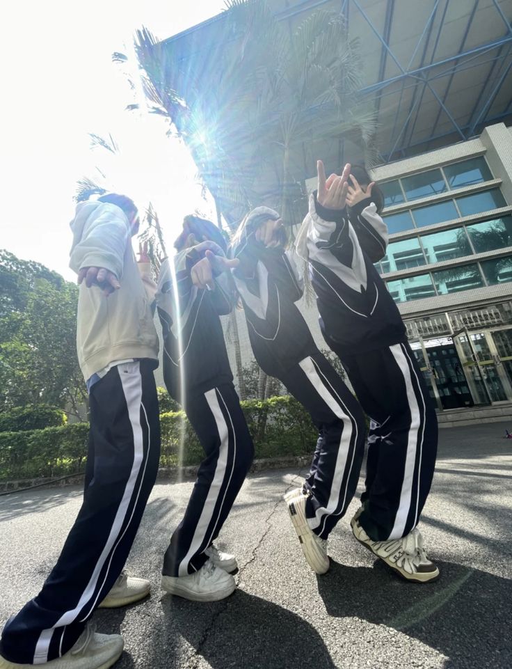 three men in black and white striped pants are standing on the street with their hands up