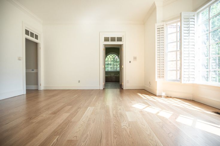 an empty room with wooden floors and white walls