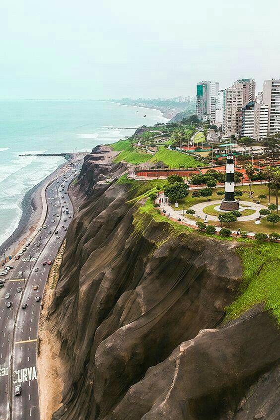 an aerial view of a beach with cars driving on the road