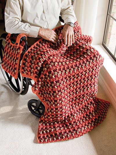 a man sitting in a wheel chair holding a crocheted blanket