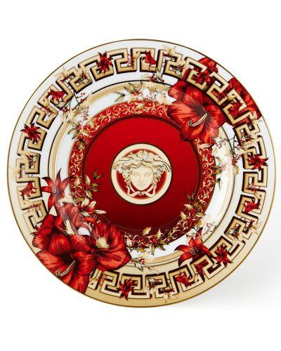 a red and gold plate with flowers on the side, in front of a white background