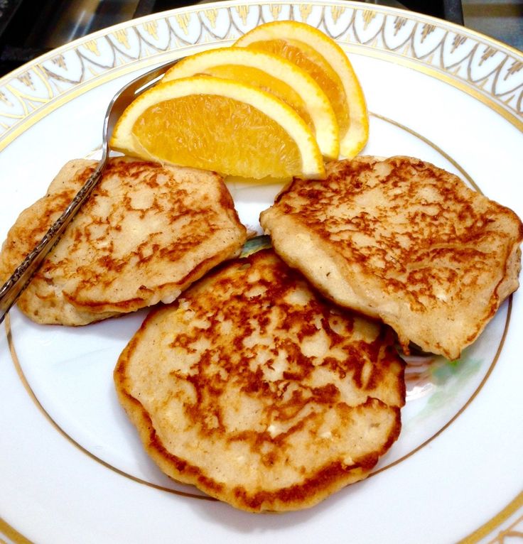 three pancakes on a plate with orange slices